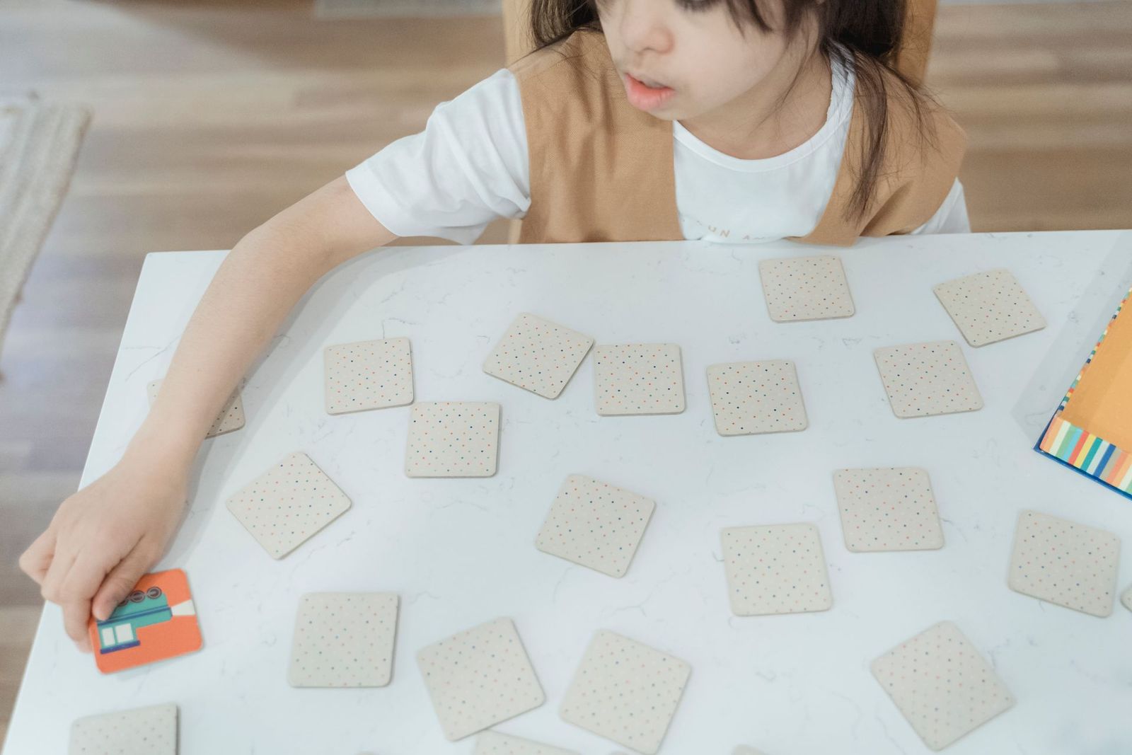 Child turning over cards in a memory matching game on a white table