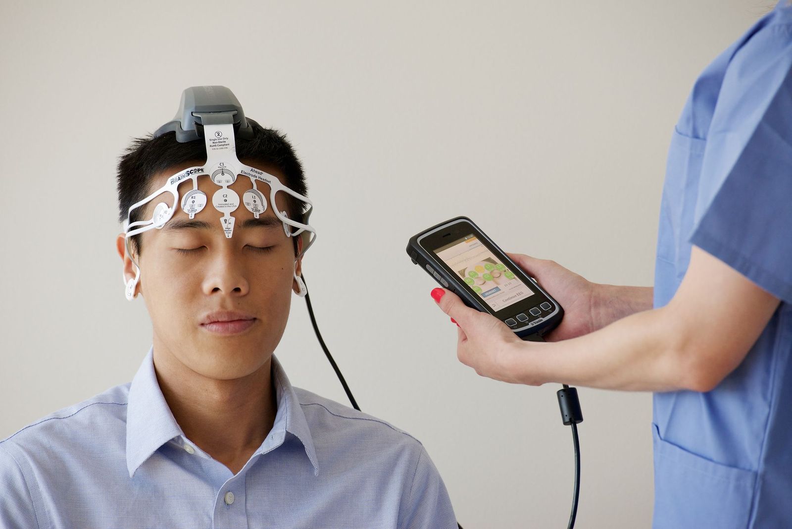 Clinician recording brain signals from a man wearing an EEG headset