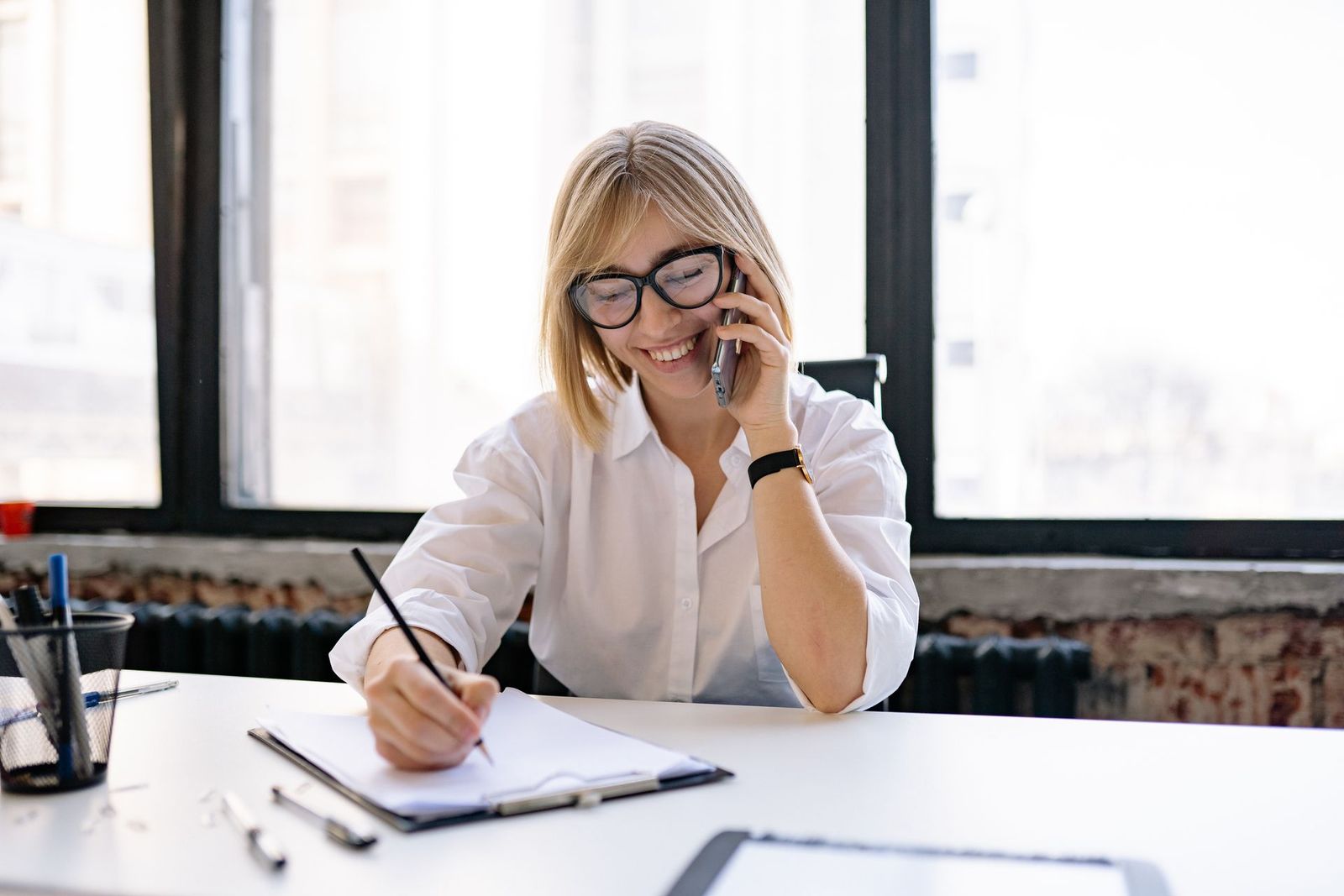 Woman taking notes during a phone call at an office desk