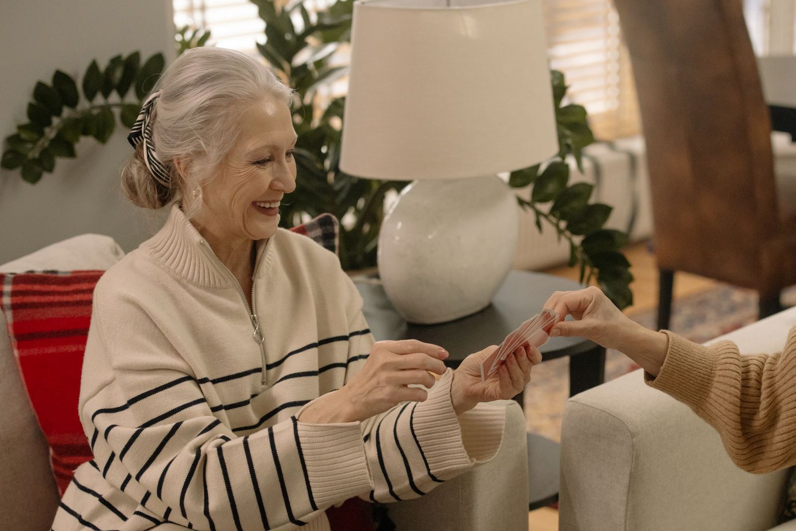 Smiling older woman playing a card game at a table
