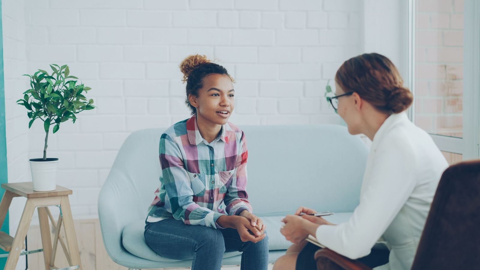Therapist and teenager talking in a bright counseling room